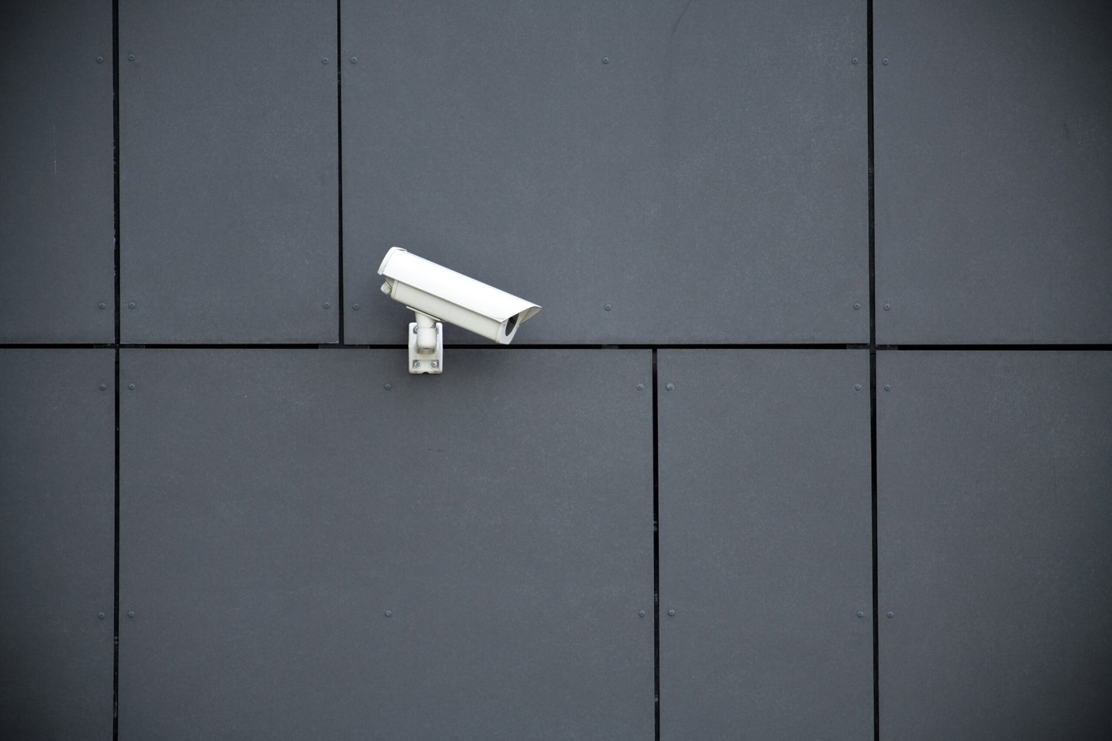 White exterior security camera on a dark grey exterior wall